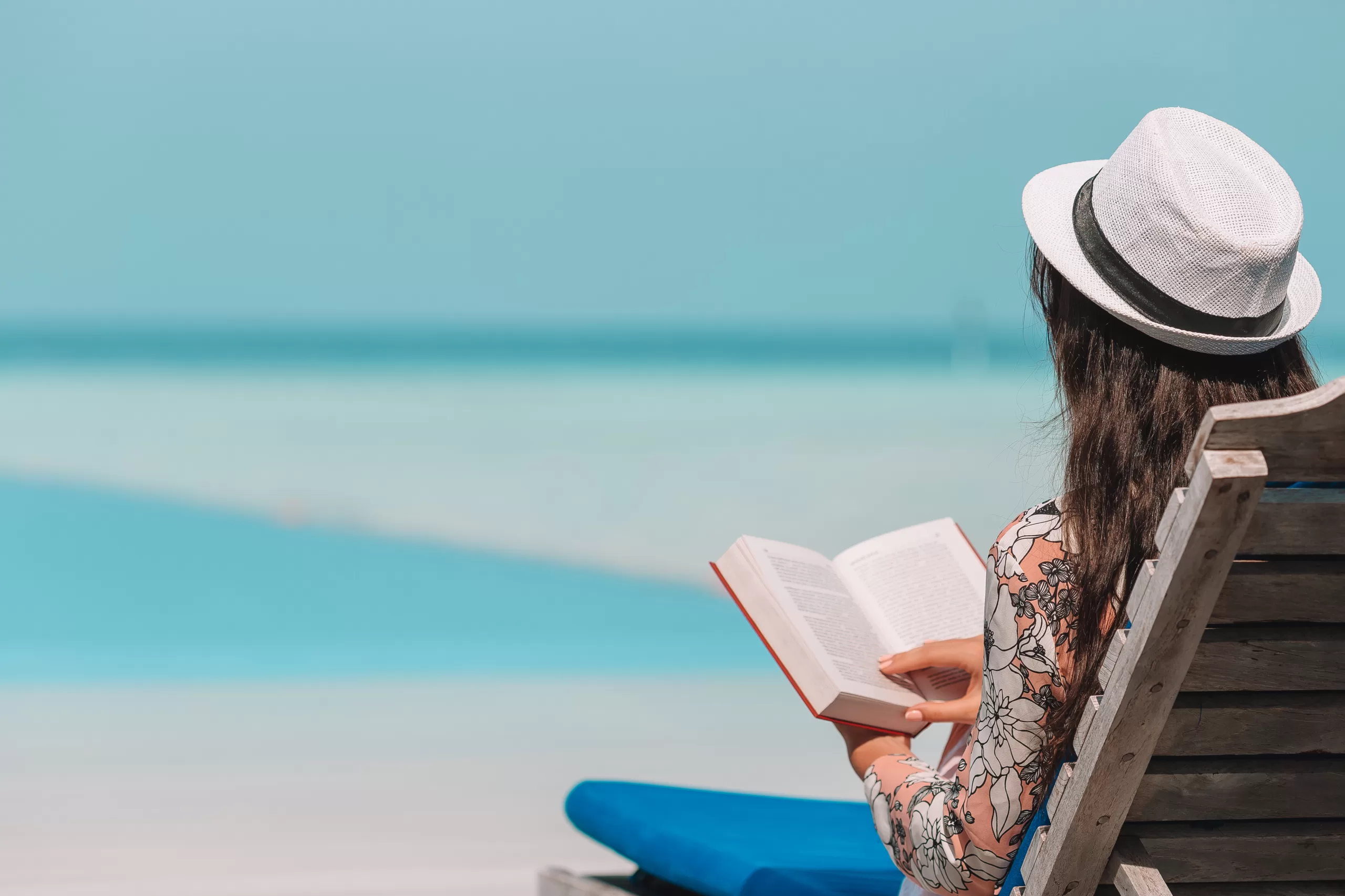 Young woman reading book during tropical maldivian beach
